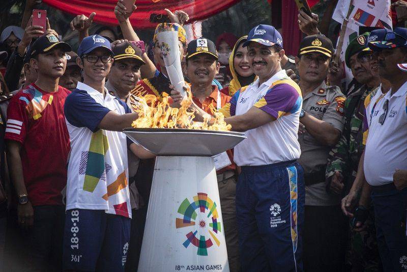 (Wali Kota Jakarta Timur M Anwar (kanan) menyerahkan obor Asian Games 2018 kepada atlet Taekwondo Priyaka Ivan Astama (kiri)) ANTARA FOTO/Aprillio Akbar