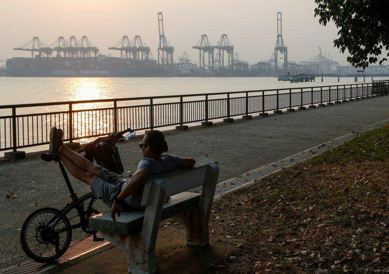 Seorang pria duduk di bangku pinggir pantai yang dipenuhi kabut di Singapura pada 12 September 2019.  ANTARA FOTO/REUTERS/Feline Lim
