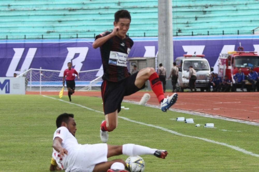 Gelandang Persipura, Oh In-kyun (atas), melewati jegalan bek PSM Hendra Wijaya (bawah) dalam lanjutan Grup C Piala Presiden 2019 di Stadion Moch, Soebroto Magelang pada Minggu (10/3/2019). (PSSI.org)