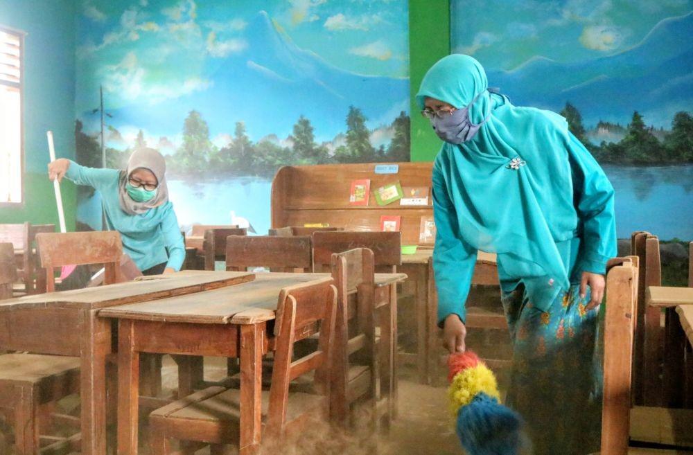 Beberapa guru tampak membersihkan debu di ruang kelas sebuah sekolah di Kota Batu. IDN Times/ Alfi Ramadana
