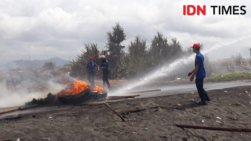 Petugas padamkan api dari ban yang dubakar petambak. IDN Times/Daruwaskita