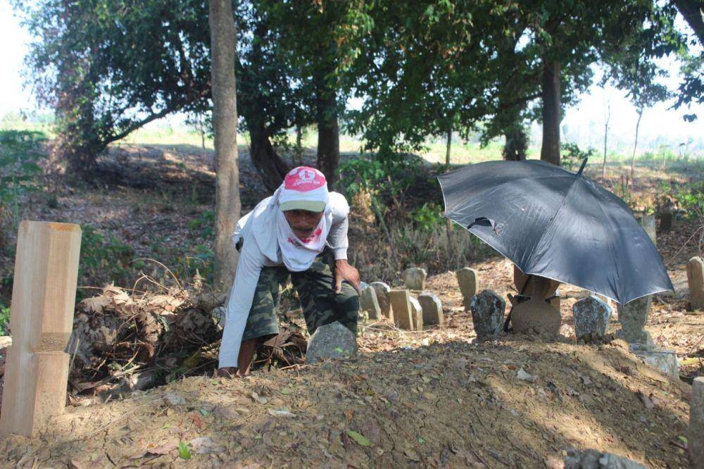 Seorang warga membersihkan makam Wartim, pria yang meninggal dunia karena kecelakaaan di Brondong. IDN Times
