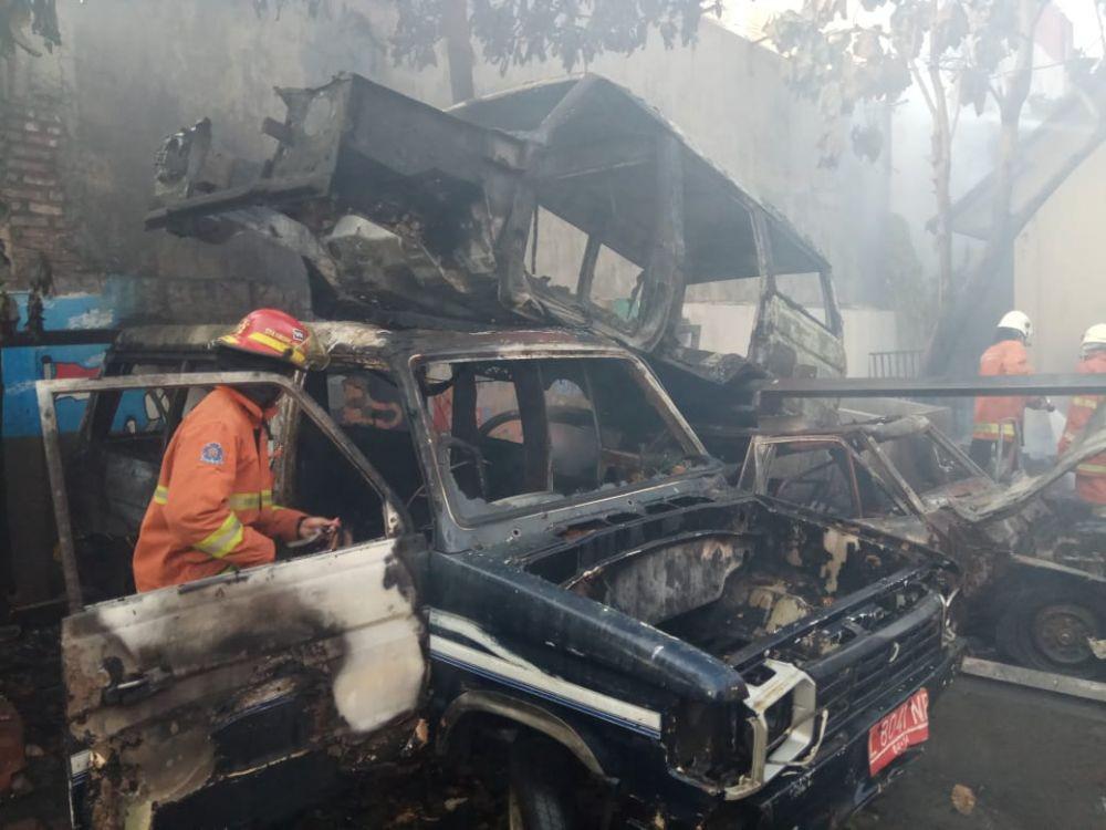 Salah seorang petugas PMK memeriksa satu mobil yang terbakar di SMKN 2 Surabaya, Minggu (1/12). Dok. Dinas Pemadam Kebakaran Kota Surabaya