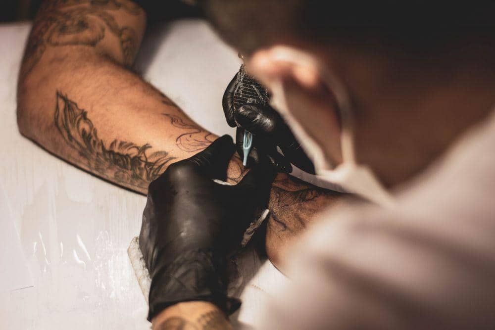 Ilustrasi seorang seniman sedang membuat tato. unsplash.com/Lucas Lenzi