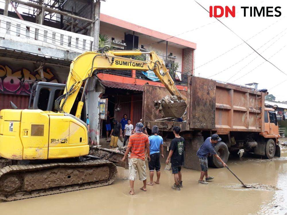 Alat berat sedang mengangkut sampah paska banjir di perumahan pondok gede permai (IDN Times/Fitang Budhi Adhitia)