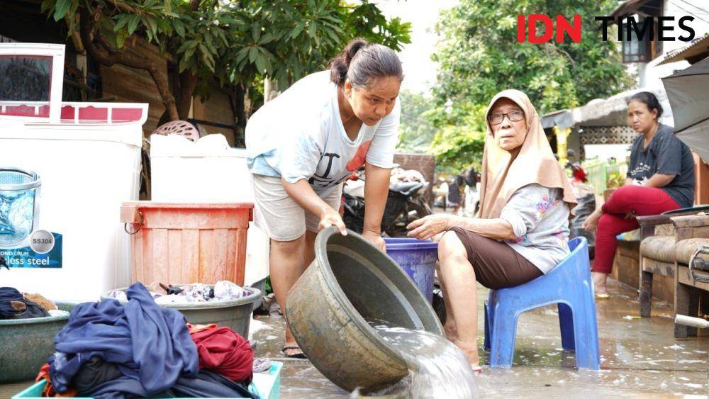 Korban banjir mencuci pakaiannya di halaman rumah. (IDN Times/Fiqih Damarjati)