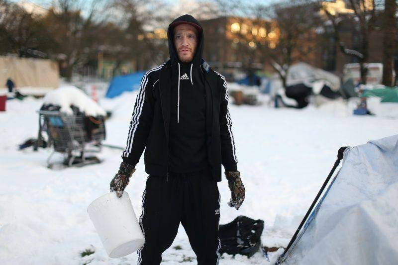 Seorang warga berpose untuk foto saat sedang menggunakan ember untuk membersihkan salju di sekeliling tendanya di perkemahan tunawisma Oppenheimer Park setelah badai menyebabkan suhu udara menyentuh titik terendah -7 derajat Celcius dan salju setinggi lebih dari 30 cm dalam semalam di pusat kota Vancouver, British Columbia, Kanada, pada 16 Januari 2020. ANTARA FOTO/REUTERS/Jesse Winter