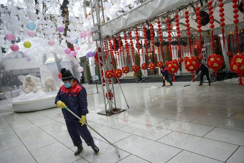 Seorang pekerja menggunakan masker saat membersihkan lapangan di tengah hujan salju, saat mewabahnya virus corona di negara tersebut, pada Hari Valentine di wilayah perbelanjaan Sanlitun di Beijing, Tiongkok, pada 14 Februari 2020. ANTARA FOTO/REUTERS/Tingshu Wang