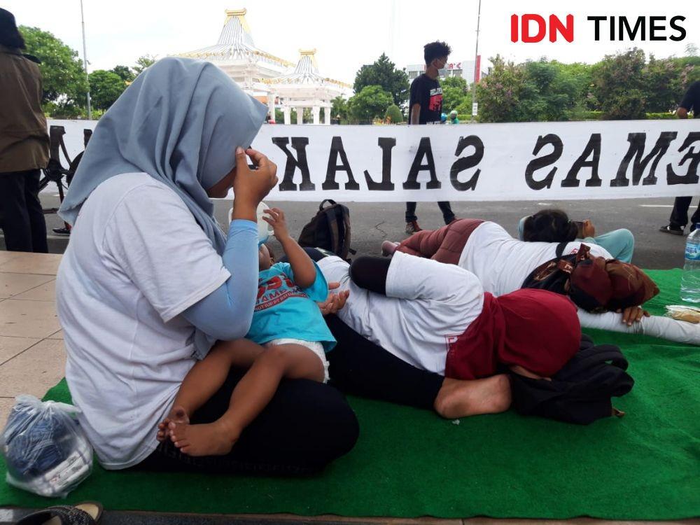 Suasana penantian dimulainya aksi penolakan tambang emas Banyuwangi di depan Kantor Gubernur Jatim. Tampak para ibu tak lelah mengikuti aksi meski harus mengurus anak mereka juga. IDN Times/Fitria Madia