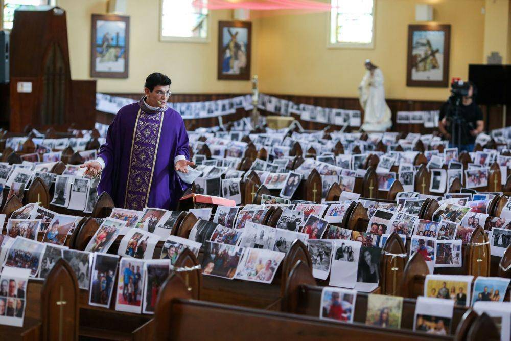 Pendeta Katolik Reginaldo Manzotti mengadakan misa yang disiarkan langsung di televisi, dengan foto para jemaat di deretan kursi gereja di gereja Santuario de Nossa Senhora de Guadalupe saat penyebaran penyakit virus korona (COVID-19) di Curitiba, Brazil, Sabtu (21/3/2020) (ANTARA FOTO/Rodolfo Buhrer)