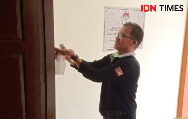 Seorang staf KPU PPU membersihkan tangan menggunakan cairan sanitizer sebelum beraktifitas di kantor (IDN Times/Ervan Masbanjar)