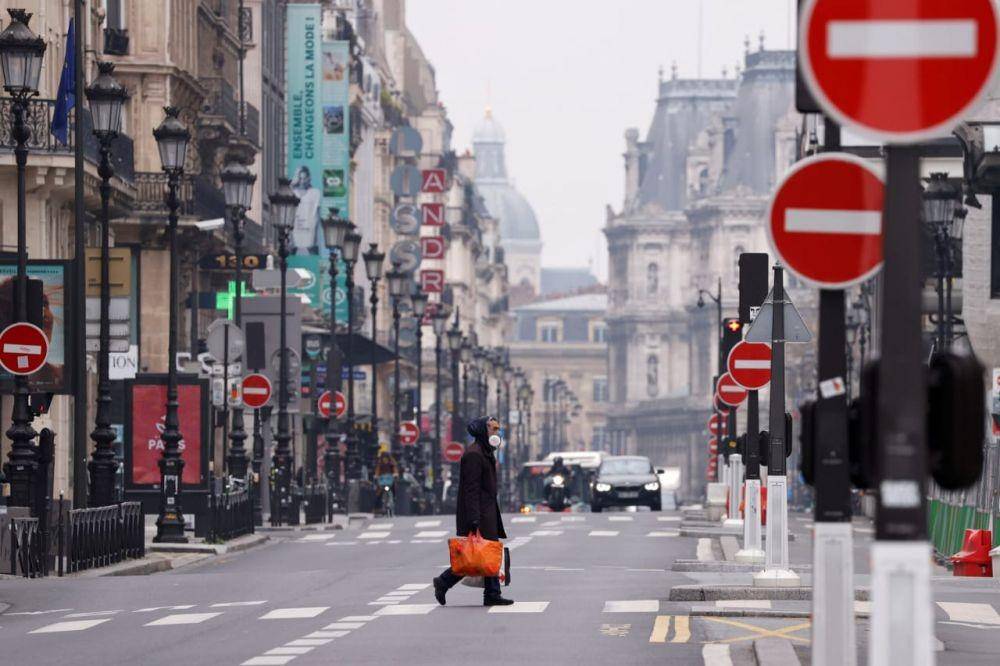 Seorang pria dengan masker menyeberang di jalan Rue de Rivoli yang kosong setelah Paris memberlakukan 'lockdown' untuk mengendalikan penyebaran virus COVID-19 di Paris, Prancis, Rabu (18/3). ANTARA FOTO/REUTERS/Christian Hartmann