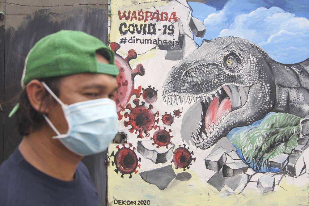 Seorang warga melintas di depan mural bertema COVID-19 di Jalan Baru, Depok, Jawa Barat, Senin (30/3/2020) (ANTARA FOTO/Asprilla Dwi Adha)