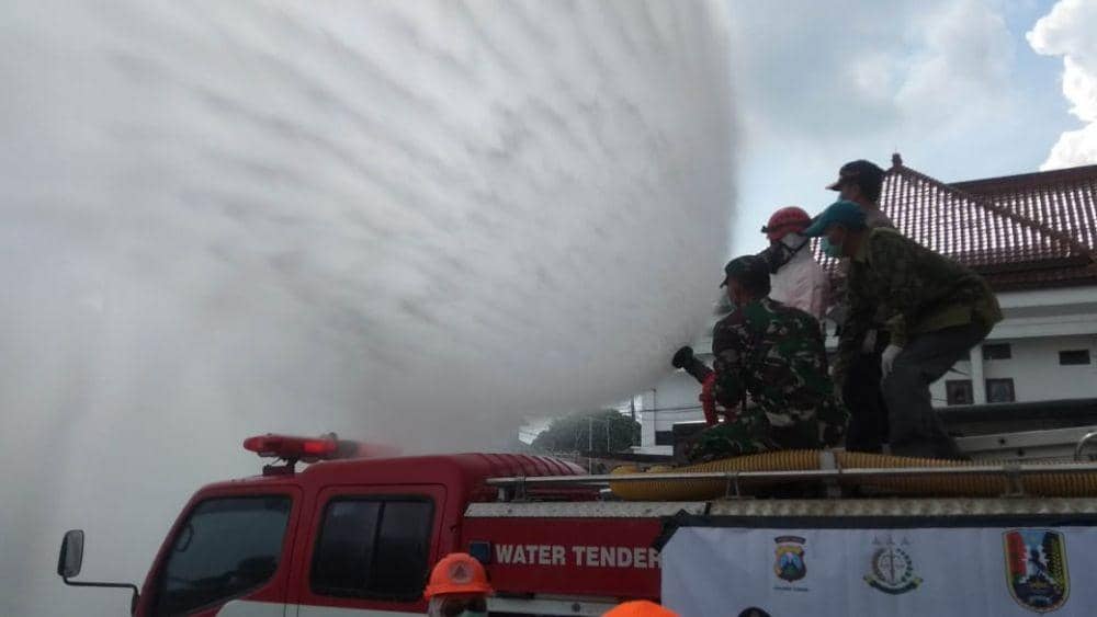 Petugas gabungan melakukan penyemprotan cairan desinfektan di halaman kantor Pemkab Tuban. IDN Times/Imron