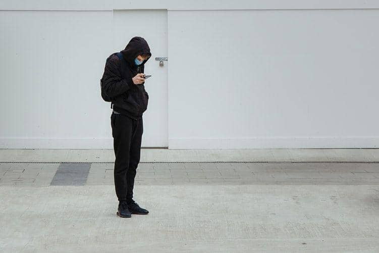 Ilustrasi pria mengenakan masker sedang menggunakan HP. unsplash.com/@markcnunes