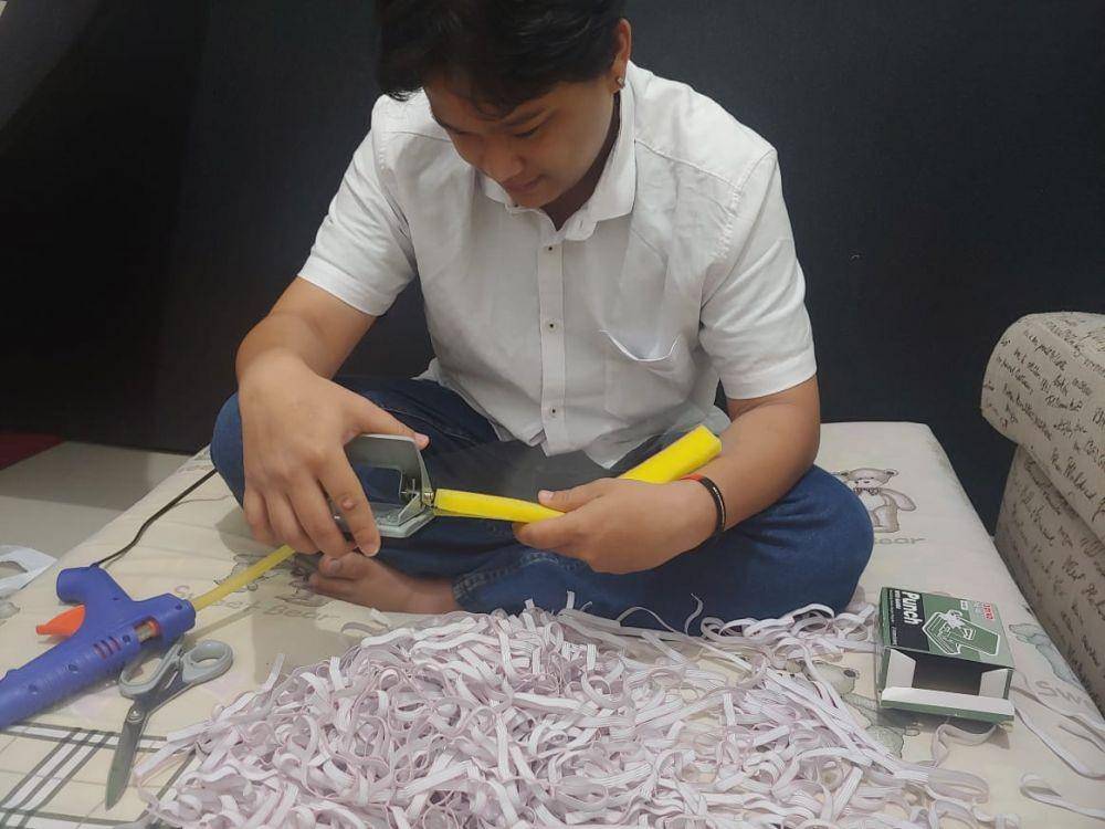 Andrew Wijaya Hidayat melubangi spons sebagai bahan baku face shield. Andrew Wijaya Hidayat for IDN Times