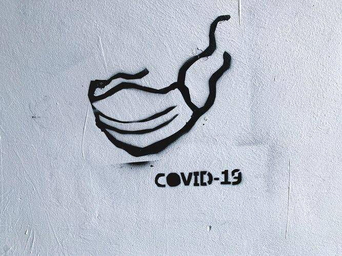 Gambar masker dan tulisan COVID-19 di tembok. unsplash.com/@adamsky1973