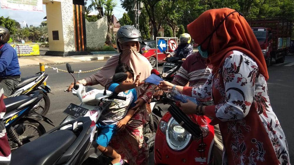 Salah satu PNS di Lamongan membagikan masker pada pengendara motor. IDN Times/Imron
