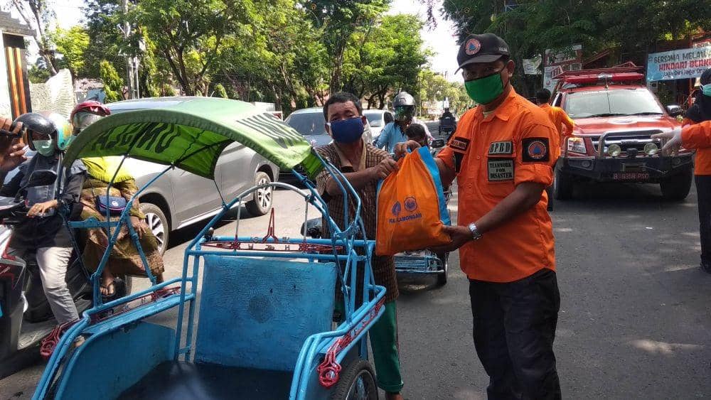 Petugas BPBD Kabupaten Lamongan bagikan bingkisan sembako pada tukang becak. (IDN Times/Imron)