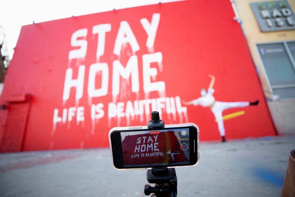 Instruktur tari Morgan Jenkins membuat video di depan sebuah mural bertema COVID-19 di Los Angeles, California, Amerika Serikat, pada 3 April 2020. ANTARA FOTO/REUTERS/Mario Anzuoni