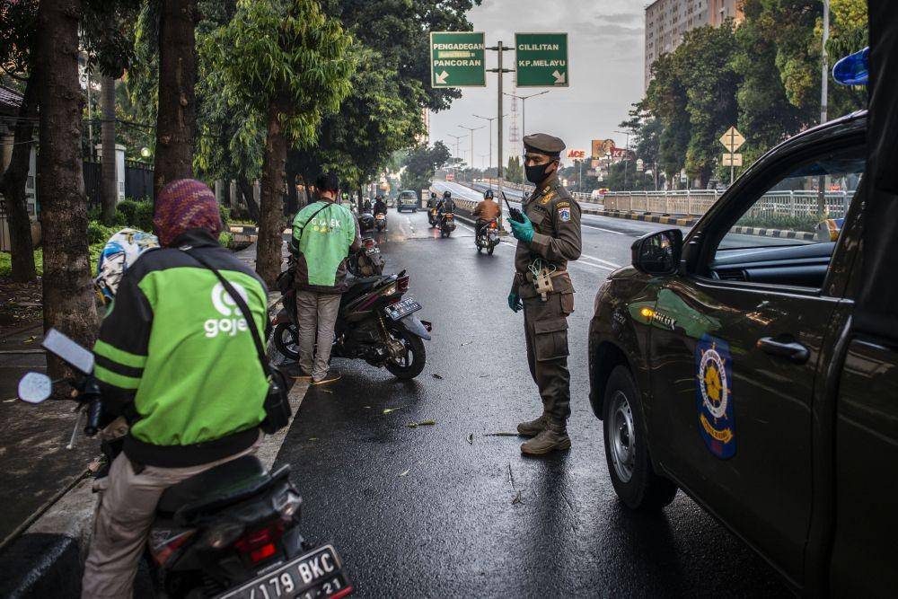 Petugas Satpol PP memberikan imbauan kepada pengemudi ojek daring saat giat Patroli Praja Peduli pada hari kedua berlangsungnya Pembatasan Sosial Berskala Besar (PSBB) di kawasan Kalibata, Jakarta, Sabtu (11/4/2020)/ANTARA FOTO/Aprillio Akbar