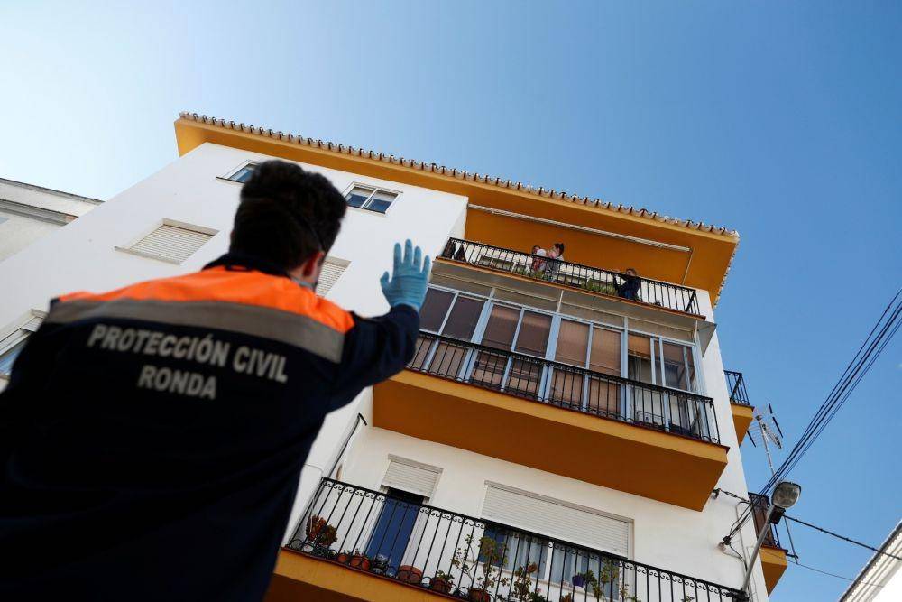 Anggota Perlindungan Sipil menyapa seorang gadis kecil yang berada di balkon di tengah penularan virus corona, di Ronda, selatan Spanyol, pada 3 April 2020. ANTARA FOTO/REUTERS/Jon Nazca 