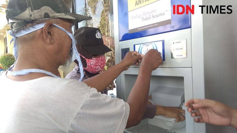 Penerima bantuan menempelkan kartu di mesin ATM beras di Makopelrasta Cirebon. (IDN Times/Wildan Ibnu)