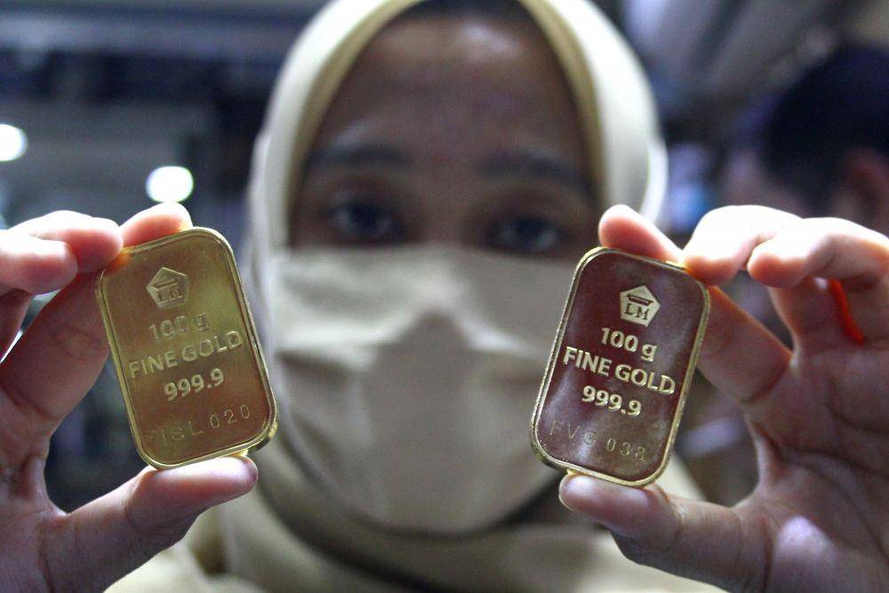 Pramuniaga menunjukkan emas batangan PT Aneka Tambang (Antam) yang kini harganya melonjak dari Rp860 ribu menjadi Rp961 ribu per gram akibat turunnya nilai tukar rupiah terhadap dollar seiring merebaknya wabah COVID-19.di sebuah gerai emas di Malang, Jawa Timur, Sabtu (18/4) (ANTARA FOTO/Ari Bowo Sucipto)