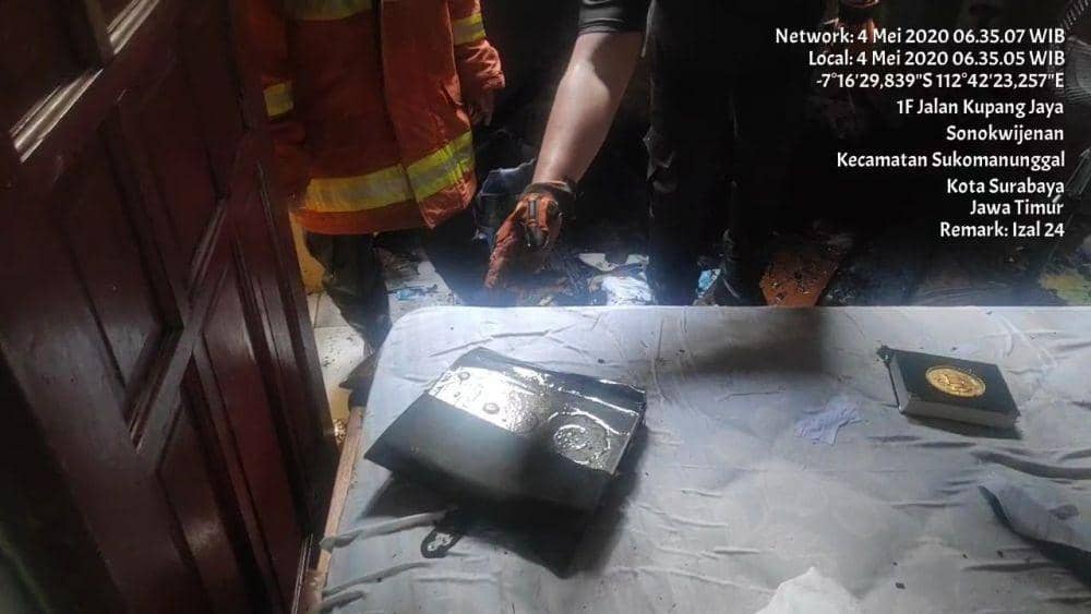 Petugas Dinas Pemadam Kebakaran Surabaya saat menunjukkan 3 Al-Quran di satu kamar yang tidak terbakar, Senin (4/5). (Dok. Dinas Pemadam Kebakaran Surabaya).