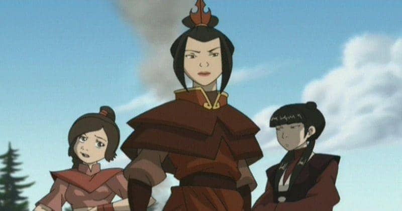 Azula berdiri di tengah dengan pakaian merah khas Negara Api, didampingi Ty Lee dan Mai di latar langit biru berawan.