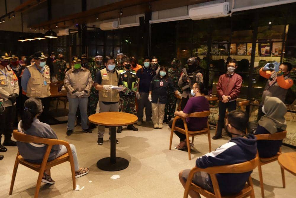 Petugas gabungan memberikan arahan kepada pengunjjng cafe agar menerapkan physical distancing. Dok/Humas Pemkot Malang