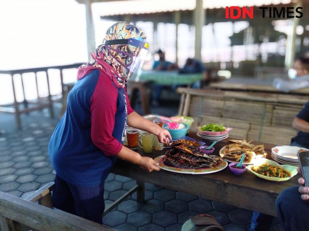 Pelayan dilengkapi face shield saat menyajikan makanan kepada tamu. IDN Times/Daruwaskita
