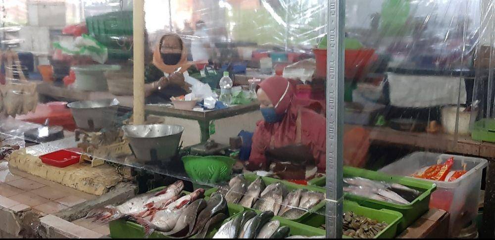 Tirai plastik menjadi sekat antara pedagang dan pembeli yang berbelanja di pasar era new normal. Dok Humas Pemkot Surabaya