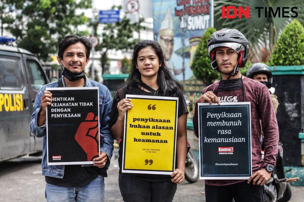 Massa memegang poster kritik di tengah aksi aksi Hari Anti Penyiksaan Internasional , Jumat (26/6). (IDN Times/Prayugo Utomo)