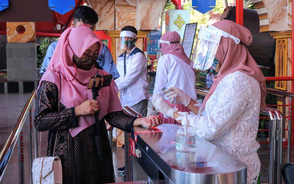 Para petugas dari Jatim Park Group melakukan pemeriksaan dan pemberian hand sanitizer kepada pengunjung yang masuk. IDN Times/ Alfi Ramadana