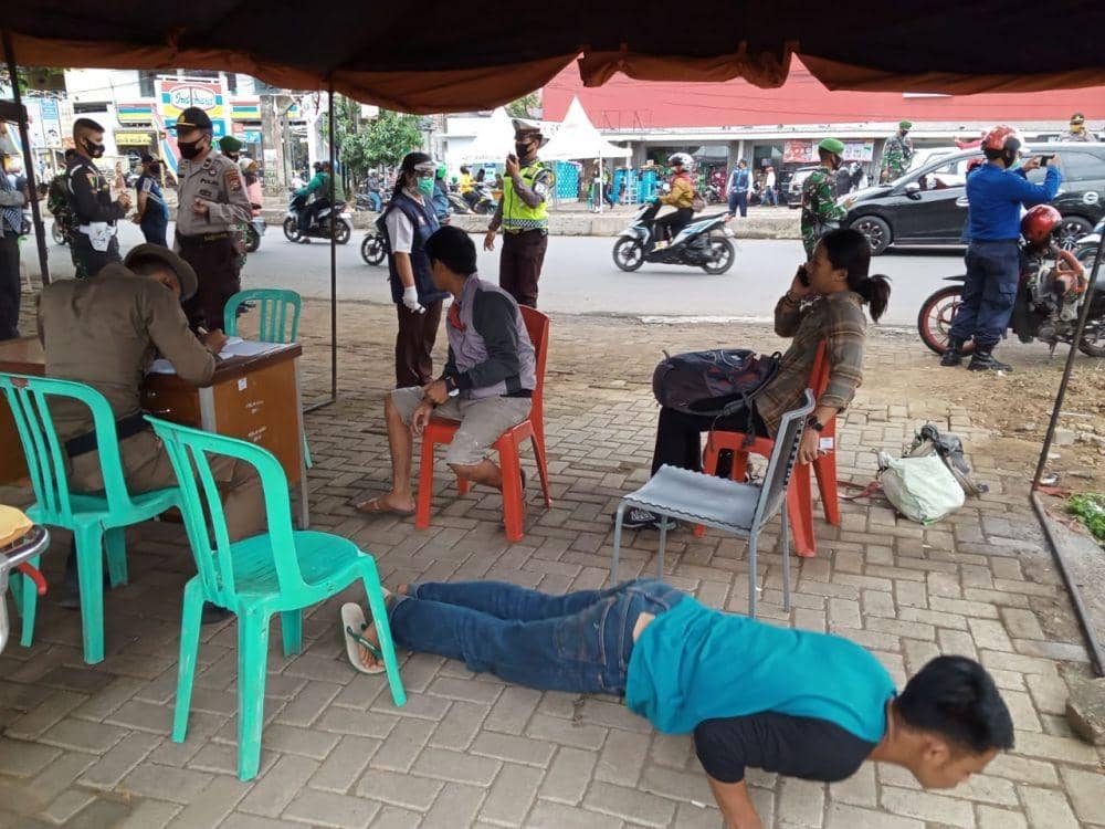 Seorang warga disuruh push up di hari pertama penerapan perwali 36/2020 di Simpang Lima perbatasan Makassar-Maros, Senin (13/7/2020). Satpol PP Makassar