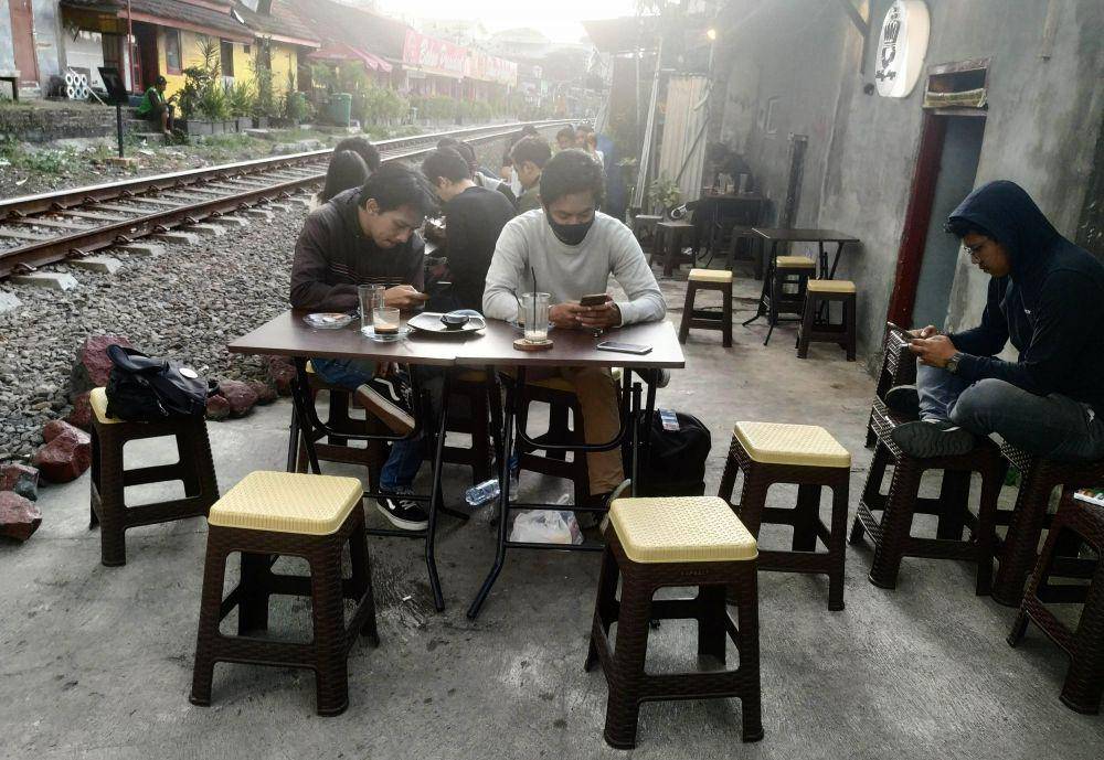 Pengunjung menikmati kopi didekat rel kereta api. IDN Times/ Alfi Ramadana