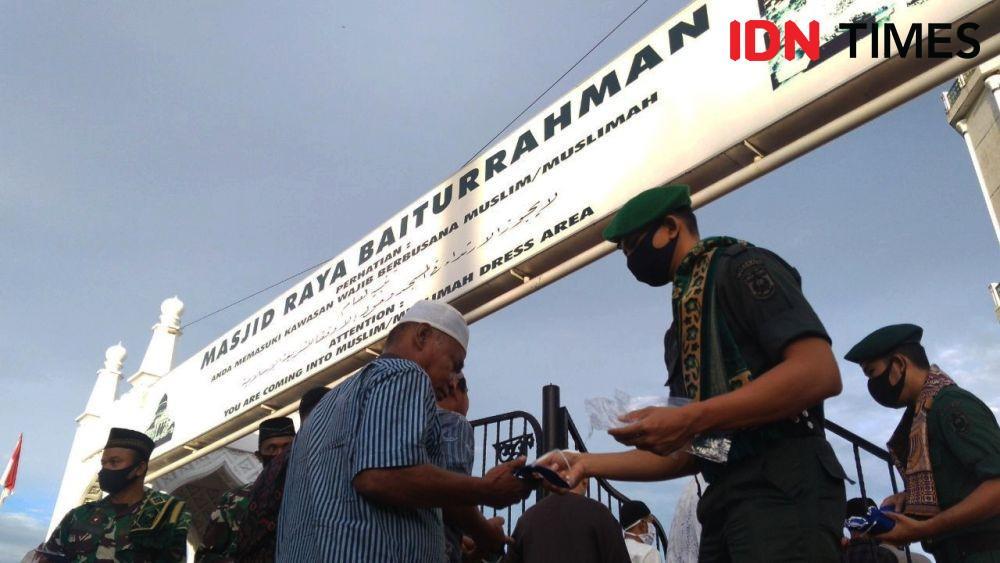 Memberikan masker kepada jemaah yang tidak membawa masker sebelum masuk ke masjid (IDN Times/Saifullah)