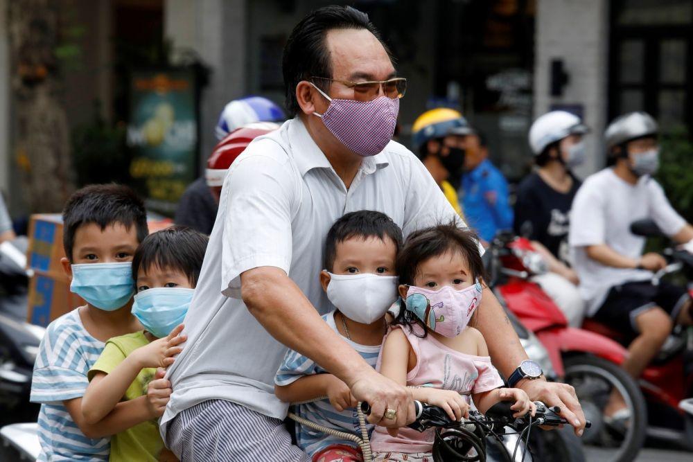 Seorang pria mengendarai sepeda membawa anak-anaknya melewati sebuah jalan ditengah mewabahnya virus corona (COVID-19), di Hanoi, Vietnam, Senin (27/7/2020). ANTARA FOTO/REUTERS/Kham