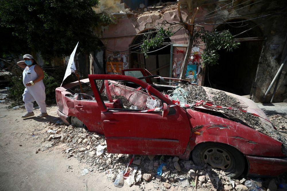 (Seorang perempuan berjalan melewati mobil rusak menyusul ledakan yang terjadi pada hari Selasa di area pelabuhan Beirut, Libanon, Minggu (9/8/2020)) ANTARA FOTO/REUTERS/Hannah McKay