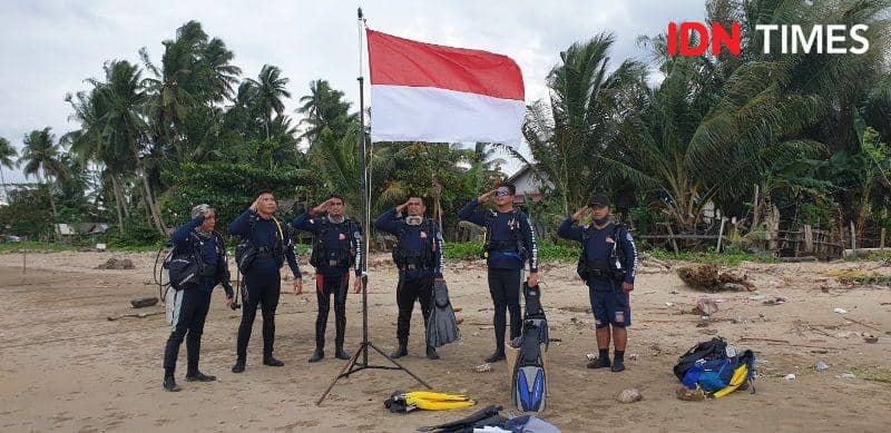 Sejumlah peselam memberikan penghormatan sebelum mengibarkan bendera di bawa laut (IDN Times/Ervan Masbanjar)