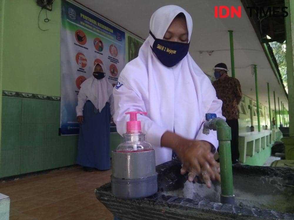 Seorang siswi SMA Negeri 2 Mejayan sedang mencuci tangan sebelum masuk ke kalas untuk mengikuti kegiatan belajar secara tatap muka pada masa uji coba, Selasa (18/8/2020). IDN Times/Nofika Dian Nugroho