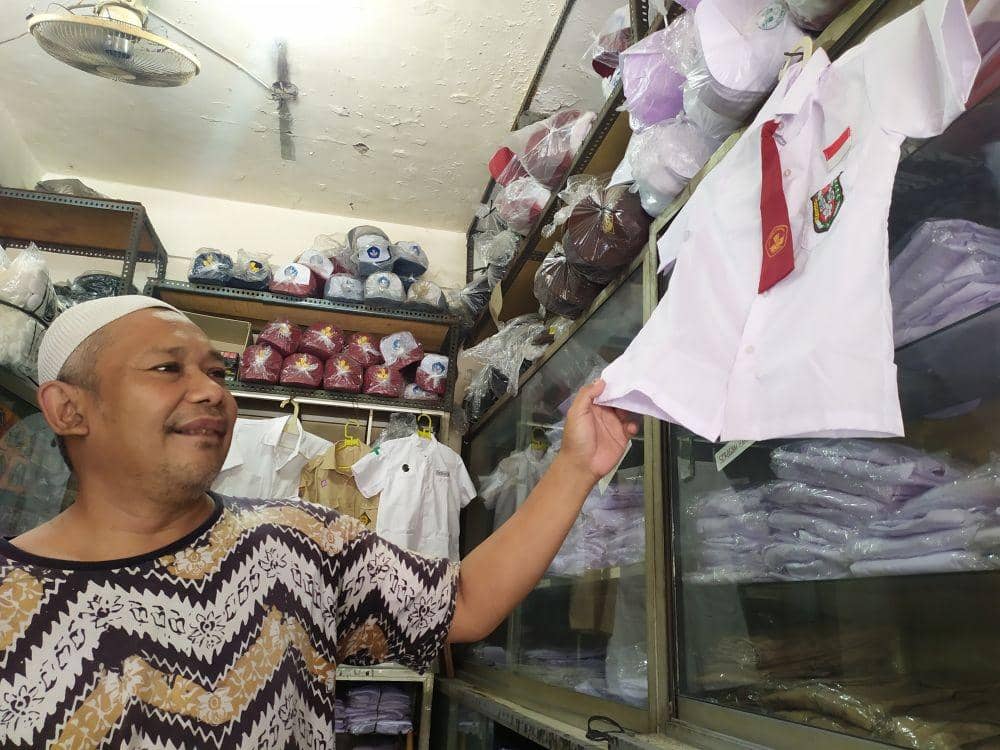Seorang pedagang di Kauman Semarang membersihkan seragam yang dipajang di tokonya. Istimewa