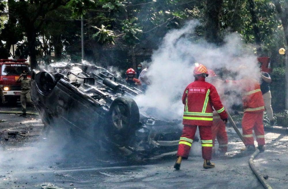 Petugas pemadam kebakaran berusaha memadamkan mobil yang dibakar. IDN Times/ Alfi Ramadana