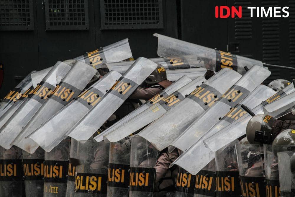 Aparat kepolisian memasang formasi bertahan dari hujan batu massa penolak Omnibus Law di DPRD Sumut, Kamis (8/10/2020). (IDN Times/Prayugo Utomo)