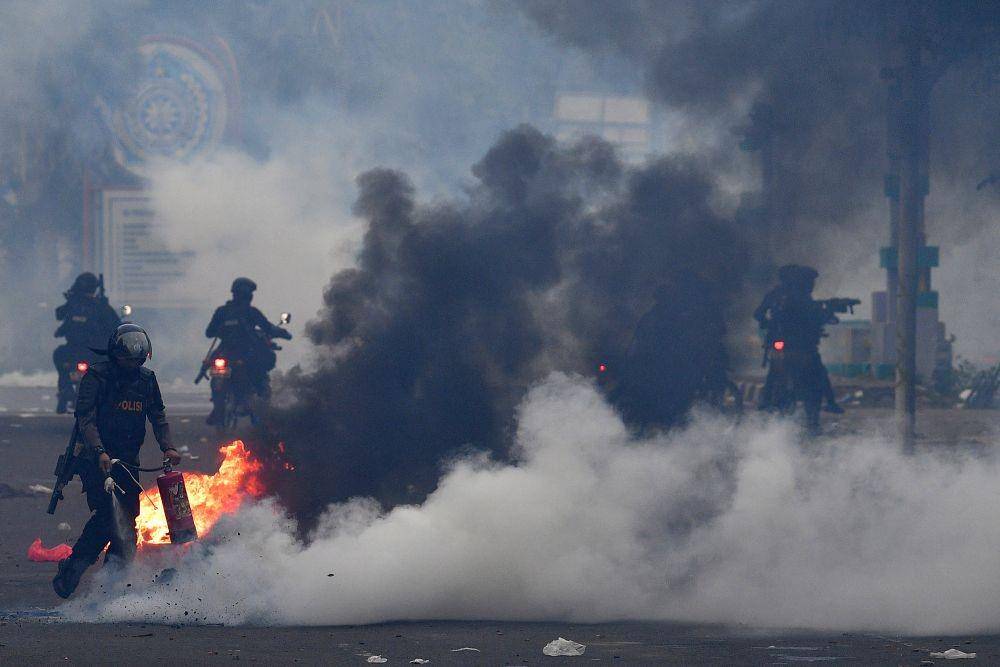 Anggota polisi memadamkan api saat berlangsung aksi menolak UU Cipta Kerja di Kwitang, Jakarta Pusat, Selasa (13/10/2020) (ANTARA FOTO/Sigid Kurniawan)