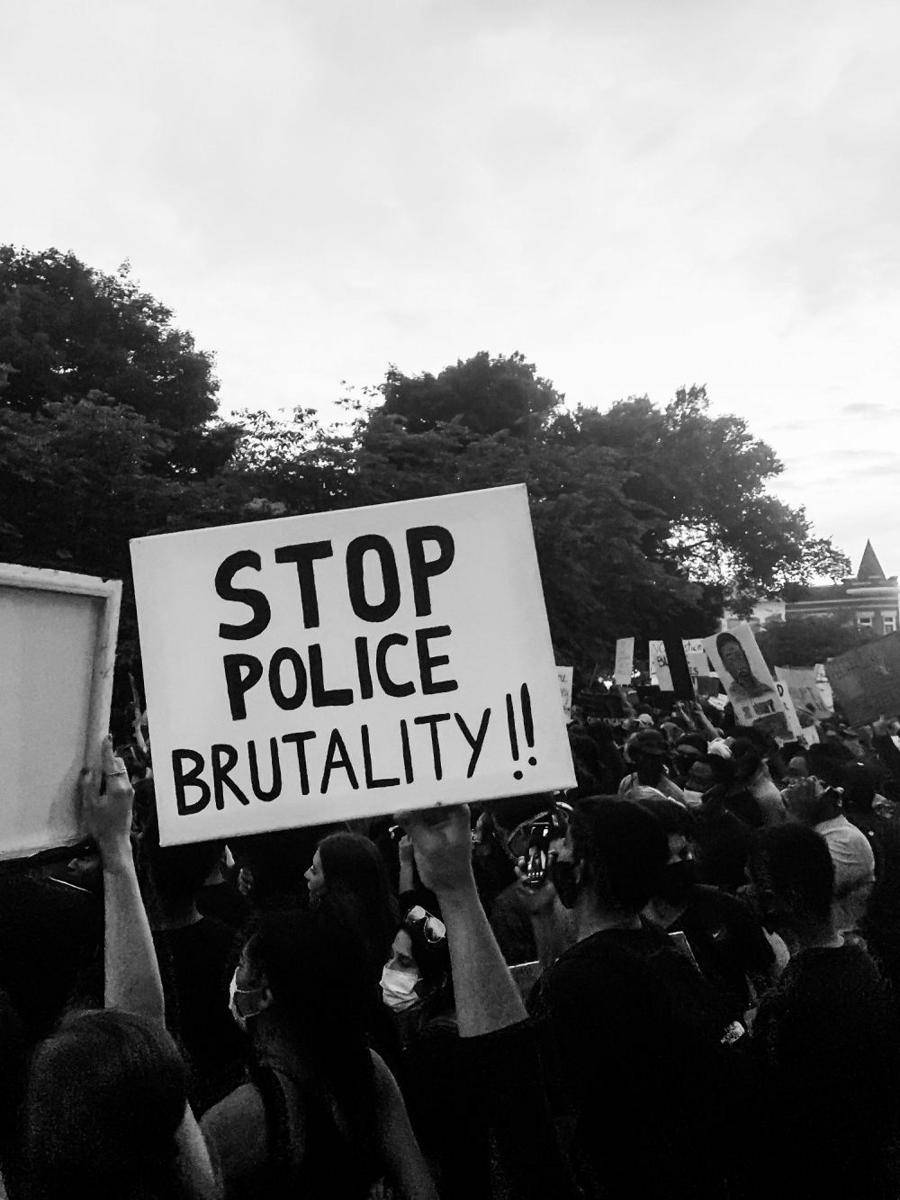 Salah seorang pengunjuk rasa mengangkat banner bertulisan "stop kebrutalan polisi". Ilustrasi. unsplash.com/Derick McKinney