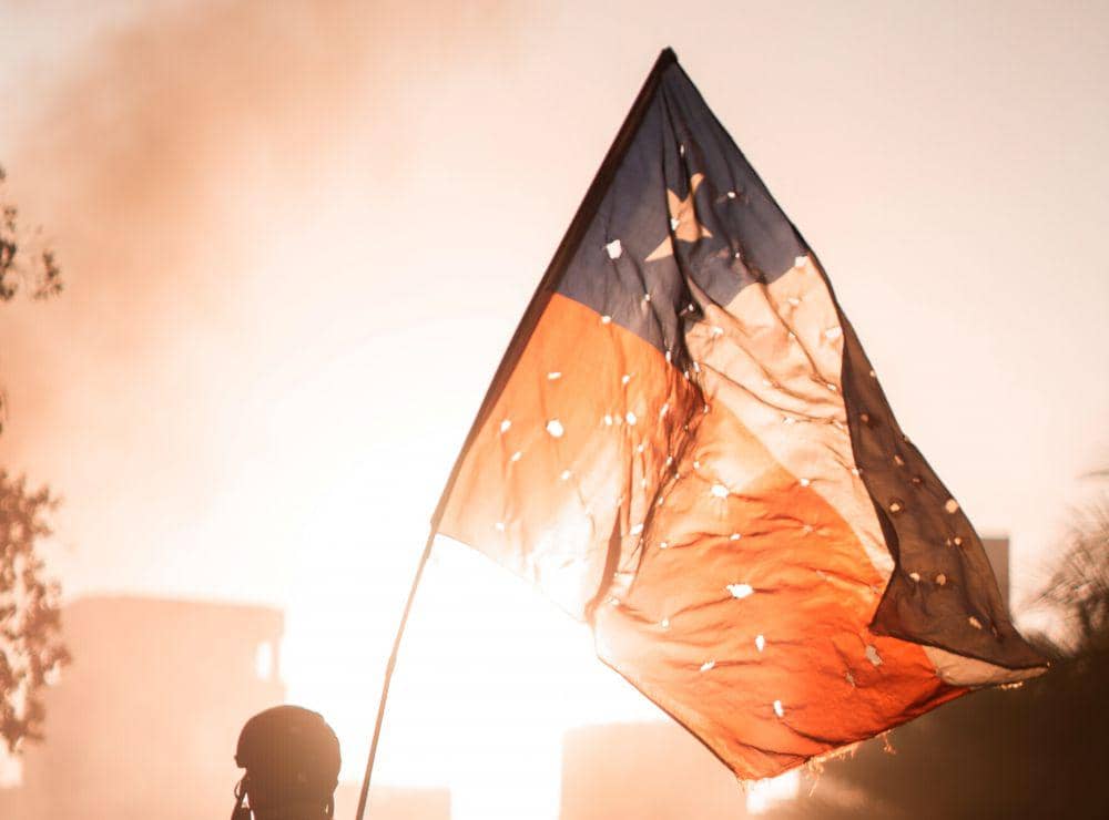 Seseorang membawa bendera Chile pada demo besar tahun 2019 lalu. Unsplash/Cristian Castillo