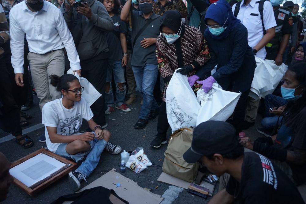 Wali Kota Surabaya Tri Rismaharini memunguti sampah di tengah aksi demo (10/11). Dokumentasi Humas Pemkot