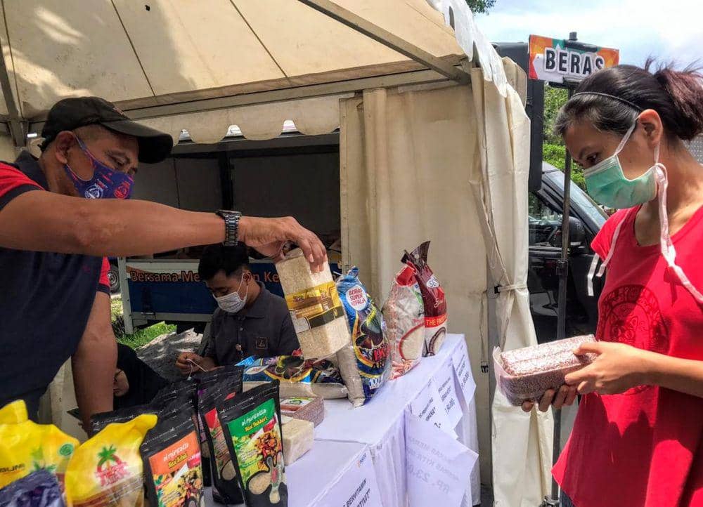 Petugas melayani warga yang berbelanja di pasar murah. 
